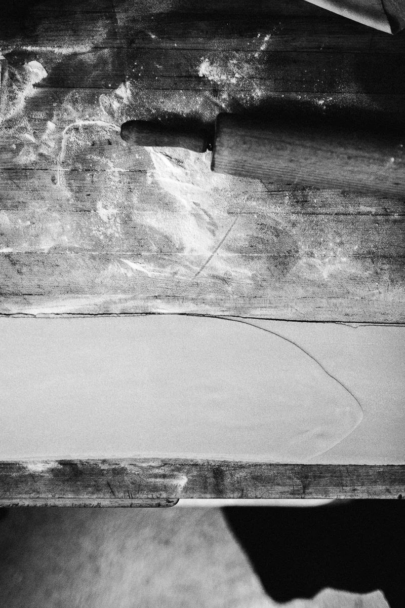 A rolling pin on a wooden surface dusted with flour and dough.