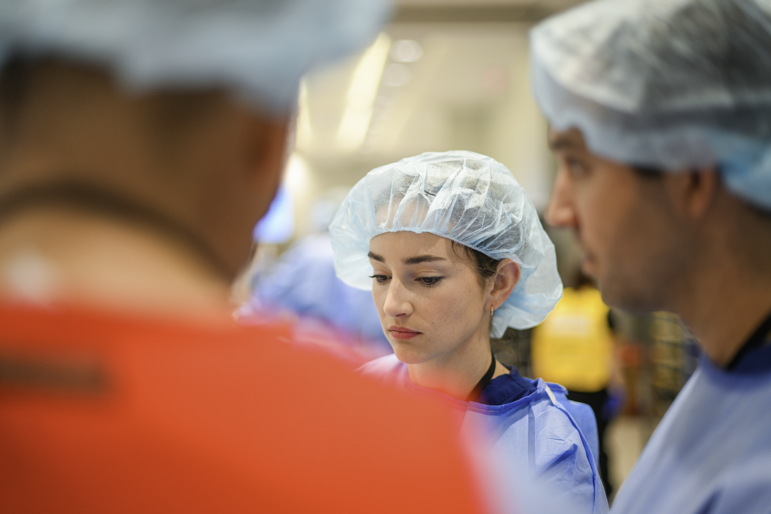 A medical team in scrubs and hair covers gathered closely in a hospital or surgical setting.