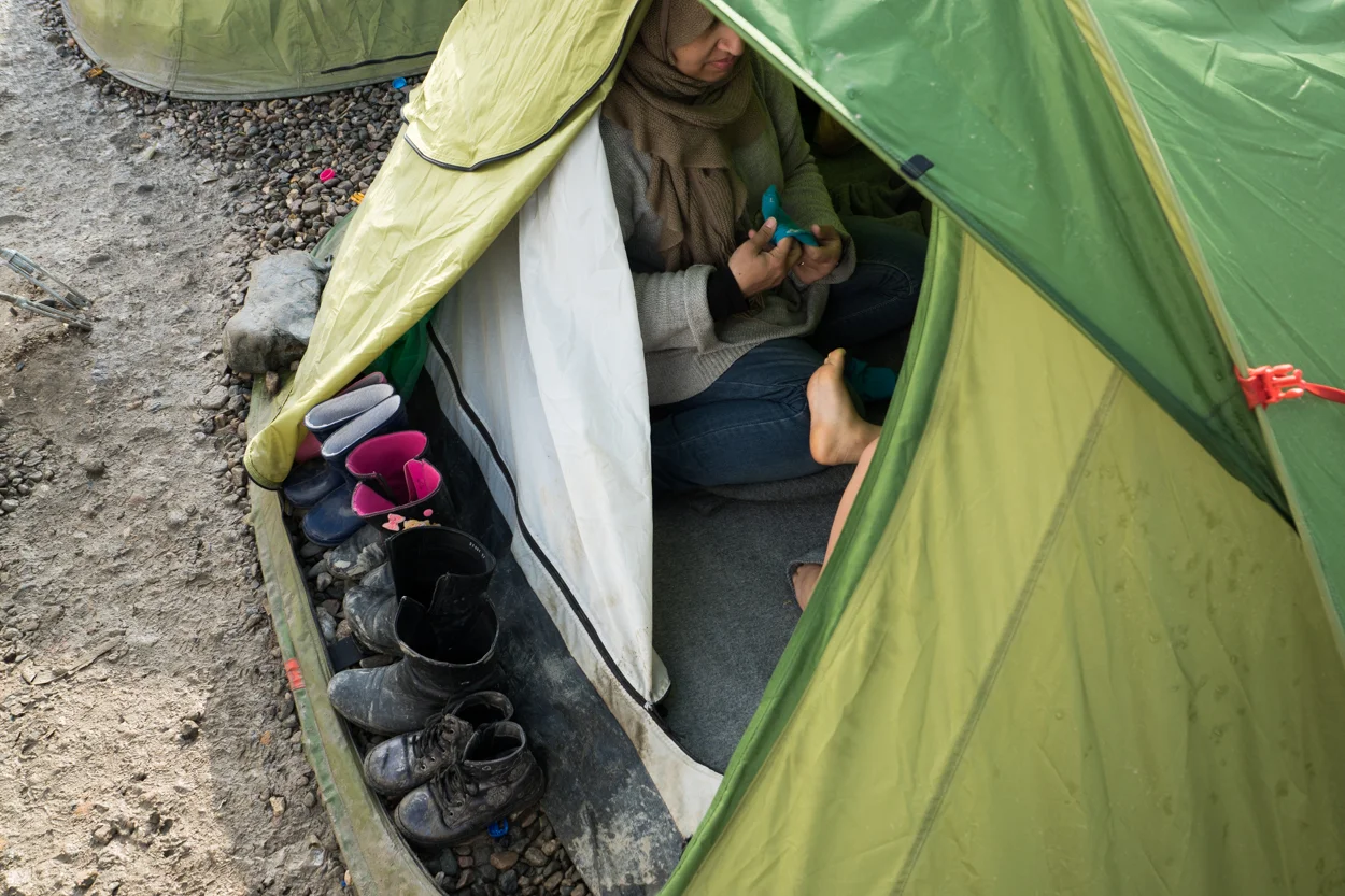 Idomeni, Greece – March 1, 2016 A woman puts a sock on a child's foot in a tent on the border with Macedonia (FYROM). Despite the squalid living conditions in Idomeni, refugee families observe the customs of home, including leaving shoes outside the tent so as not to bring dirt inside.