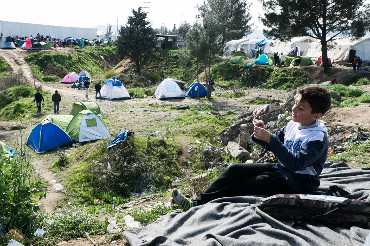 Idomeni, Greece – March 2, 2016 A child reads from a small sheet of paper in a refugee camp in Idomeni, Greece on the border with Macedonia (FYROM).