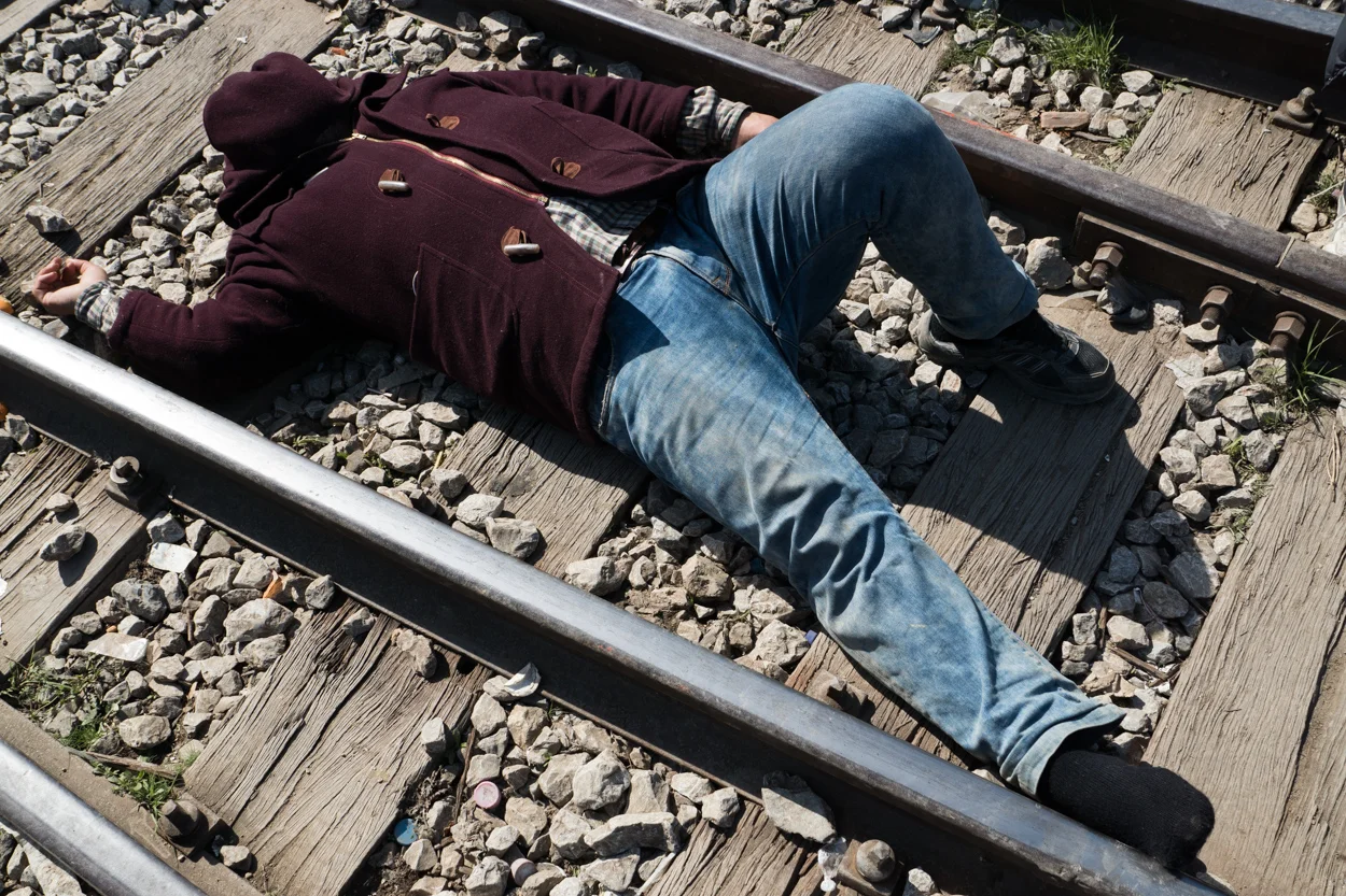 Idomeni, Greece – March 3, 2016 A man sleeps on train tracks leading to Macedonia in the refugee camp in Idomeni, Greece.