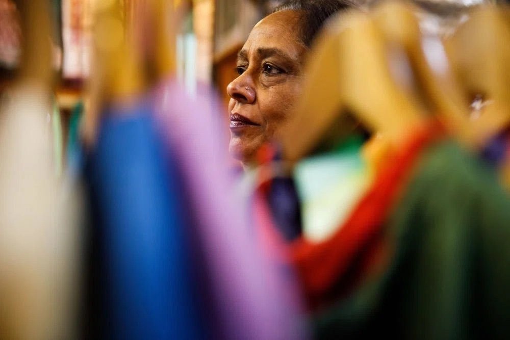 Saroj Goyal helps customers inside Dress Shoppe II, Thursday, Nov. 4, 2021 in New York. Saroj opened the shop with her late husband, Purushottam Goyal, in 1977. Saroj has run the shop full time since her husband's death in 2019 and said she is bein
