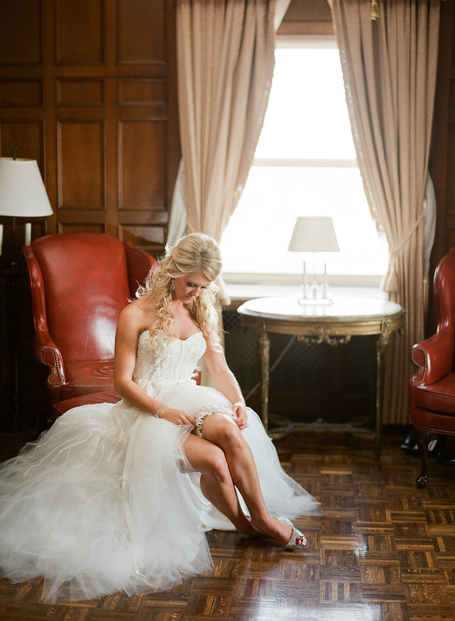 destination wedding photographer lexia frank photographs the wedding of pro NFL star football plater Bryan Bulaga as his bride puts on her garter at the Hilton Milwaukee wedding