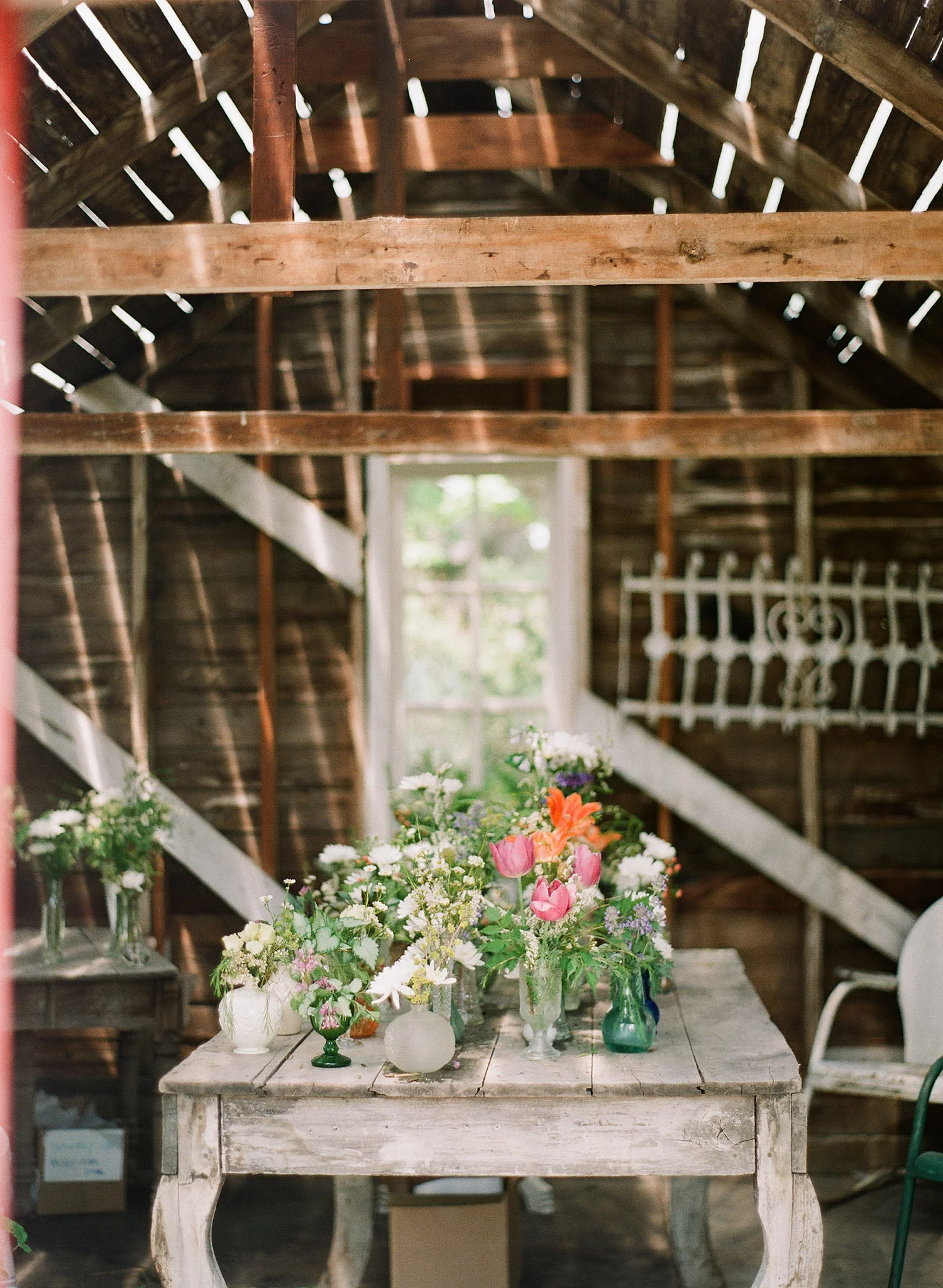 mis-matched vases for wedding flower center pieces wait in a barn while Destination Wedding photographer Lexia Frank photographs this springtime wedding on film at the Northwind Perennial Gardens in wisconsin