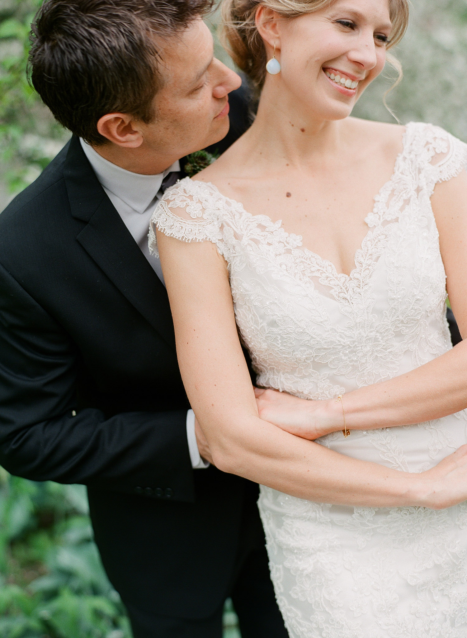 groom kisses brides neck after their first look during their springtime wedding at Northwind Perennial Gardens in wisconsin while Destination Wedding Photographer Lexia Frank photographs their wedding on film