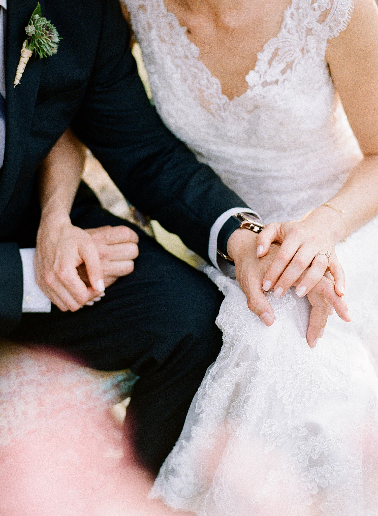 bride and groom hold hands through the pink springtime blooms at this springtime wedding at Northwind Perennial Garden - a beautiful wisconsin wedding venue - while Destination wedding photographer Lexia Frank Photographs this wedding on film