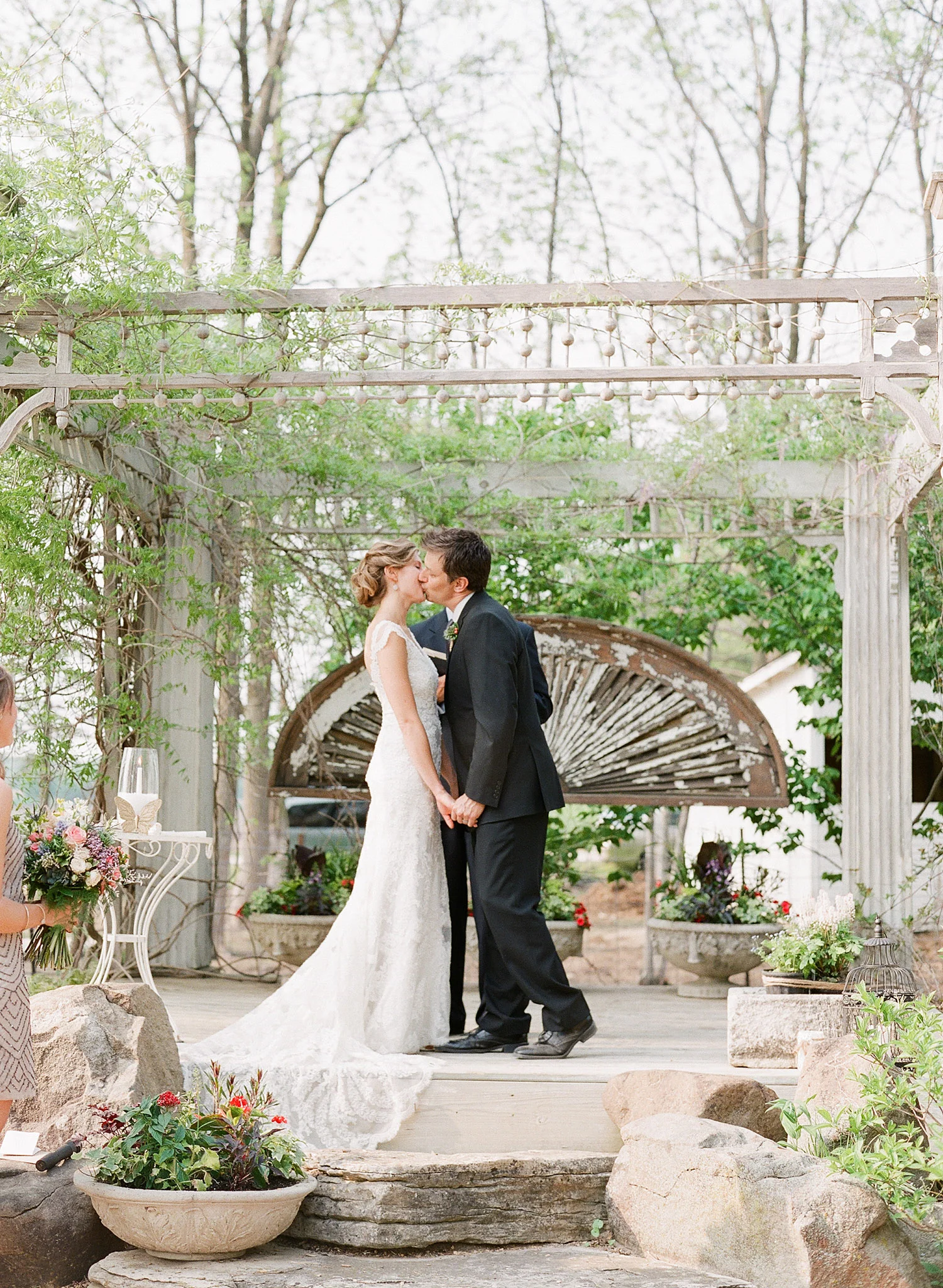bride and groom kiss at the ceremony at this springtime wedding at Northwind Perennial Garden - a beautiful wisconsin wedding venue - while Destination wedding photographer Lexia Frank Photographs this wedding on film