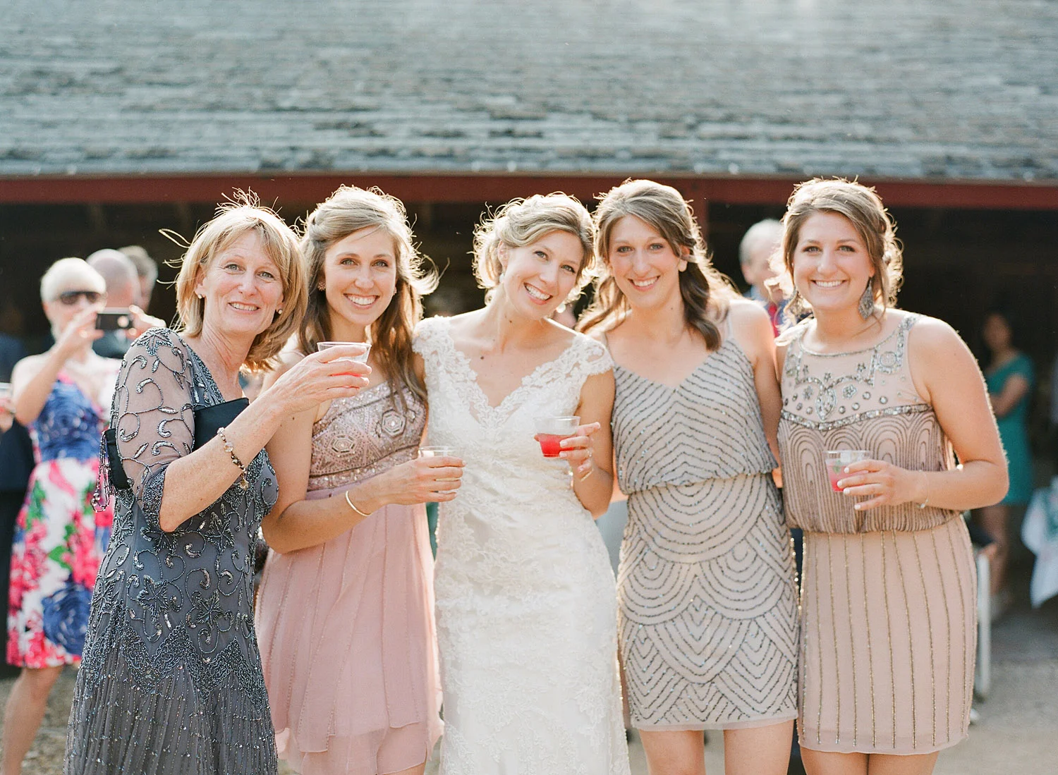 bridesmaids share a cocktail at the outdoor reception at Northwind Perennial Gardens - a gorgeous outdoor wedding venue in wisconsin - while film photographer Lexia Frank Photographs this destination wedding