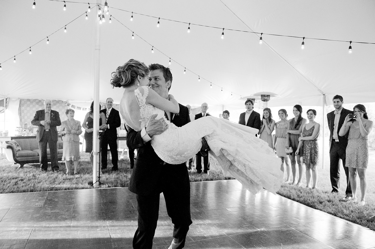 groom carries bride into the reception for their grand entrance at this springtime wedding at Northwind Perennial gardens - a wisconsin wedding venue - as a film wedding photographer Lexia Frank photographs this destination wedding on film