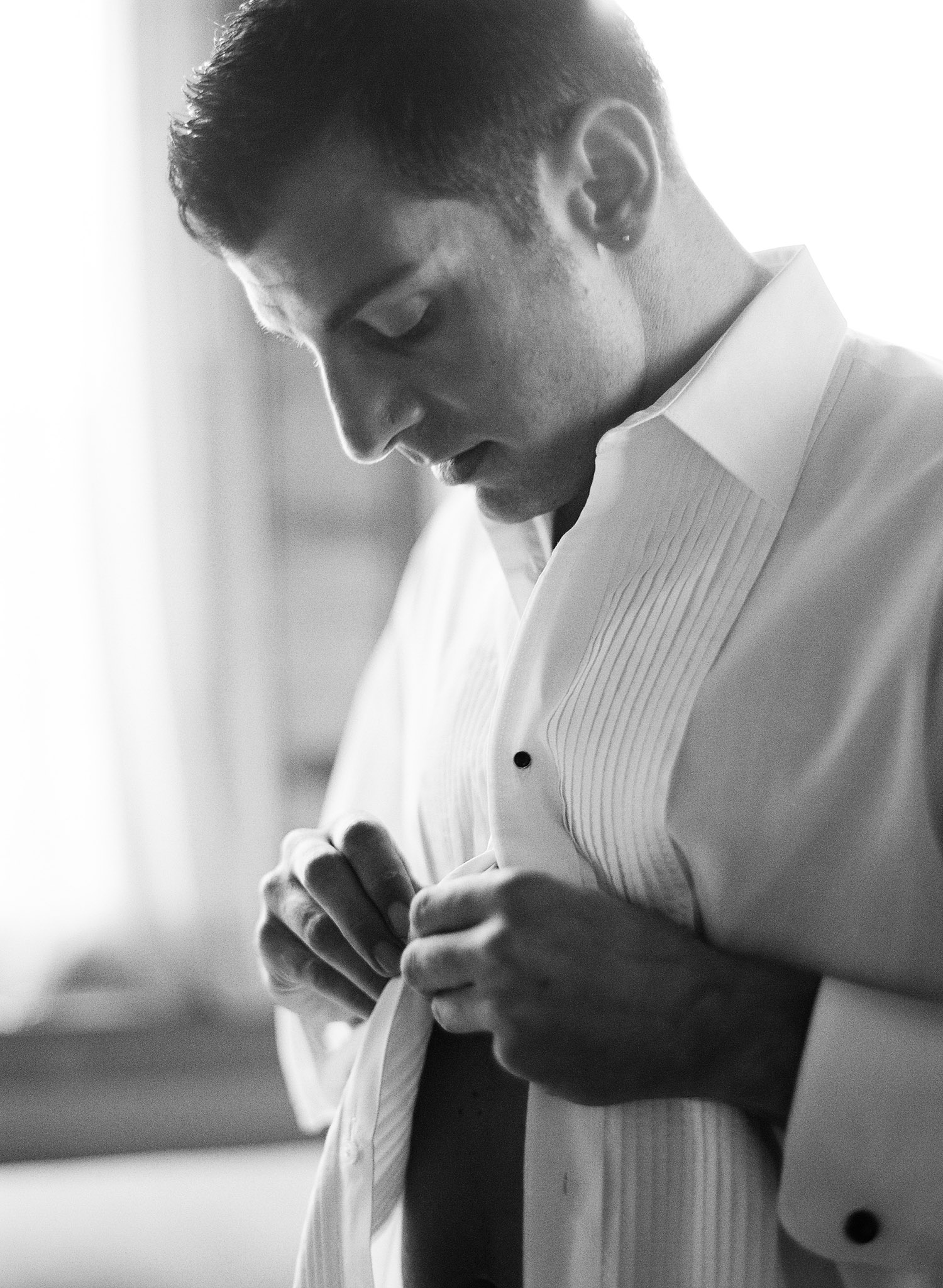 groom buttons tux shirt at the Italian Villa, The Villa Terrace, while destination wedding photographer Lexia Frank Photographs his wedding on film because she is a film photographer