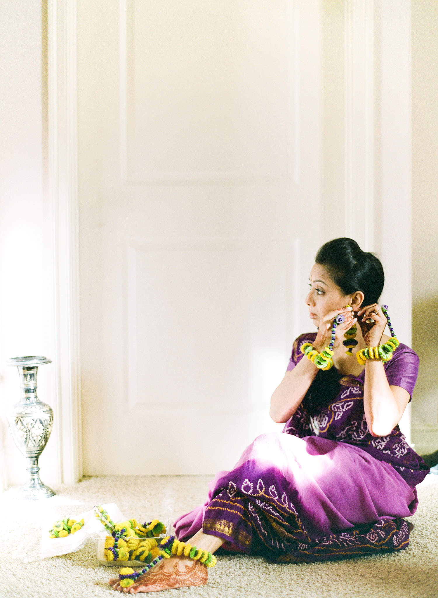 destination wedding photographer, Lexia Frank, photographs indian bride as she puts on her floral jewelry and floral tikka made of flowers at her grahashanti and pithi ceremony organized by Reveology Events. Lexia frank is a film photographer and indian wedding photographer for luxury weddings and destination weddings worldwide