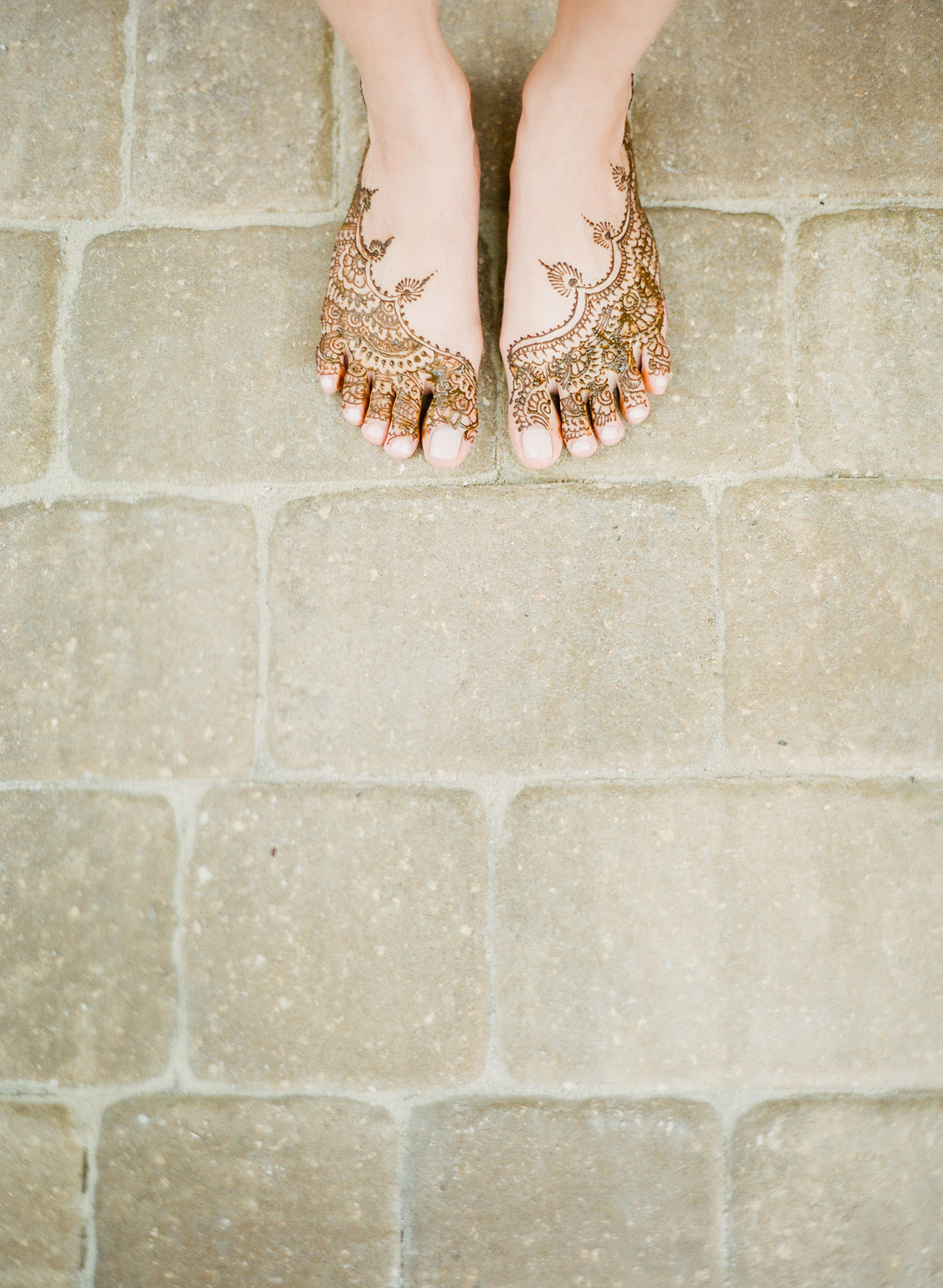 a bride shows her minimalist mehndi design on her feet at her mehndi ceremony in palm coast florida at the hammock beach resort indian wedding that Destination wedding photographer Lexia Frank- a top indian wedding photographer- photographs indian weddings on film and luxury indian weddings in florida and worldwide. 