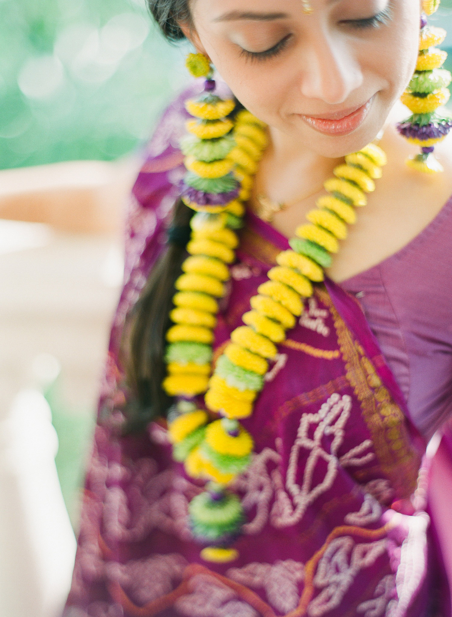 indian bride wears floral jewelry and a floral tikka and floral earrings and a purple sari at this mehndi ceremony in palm coast florida at the hammock beach resort indian wedding. Photographed by destination wedding photographer Lexia Frank, a top indian wedding photographer photographing indian weddings on film and shooting luxury indian weddings worldwide 