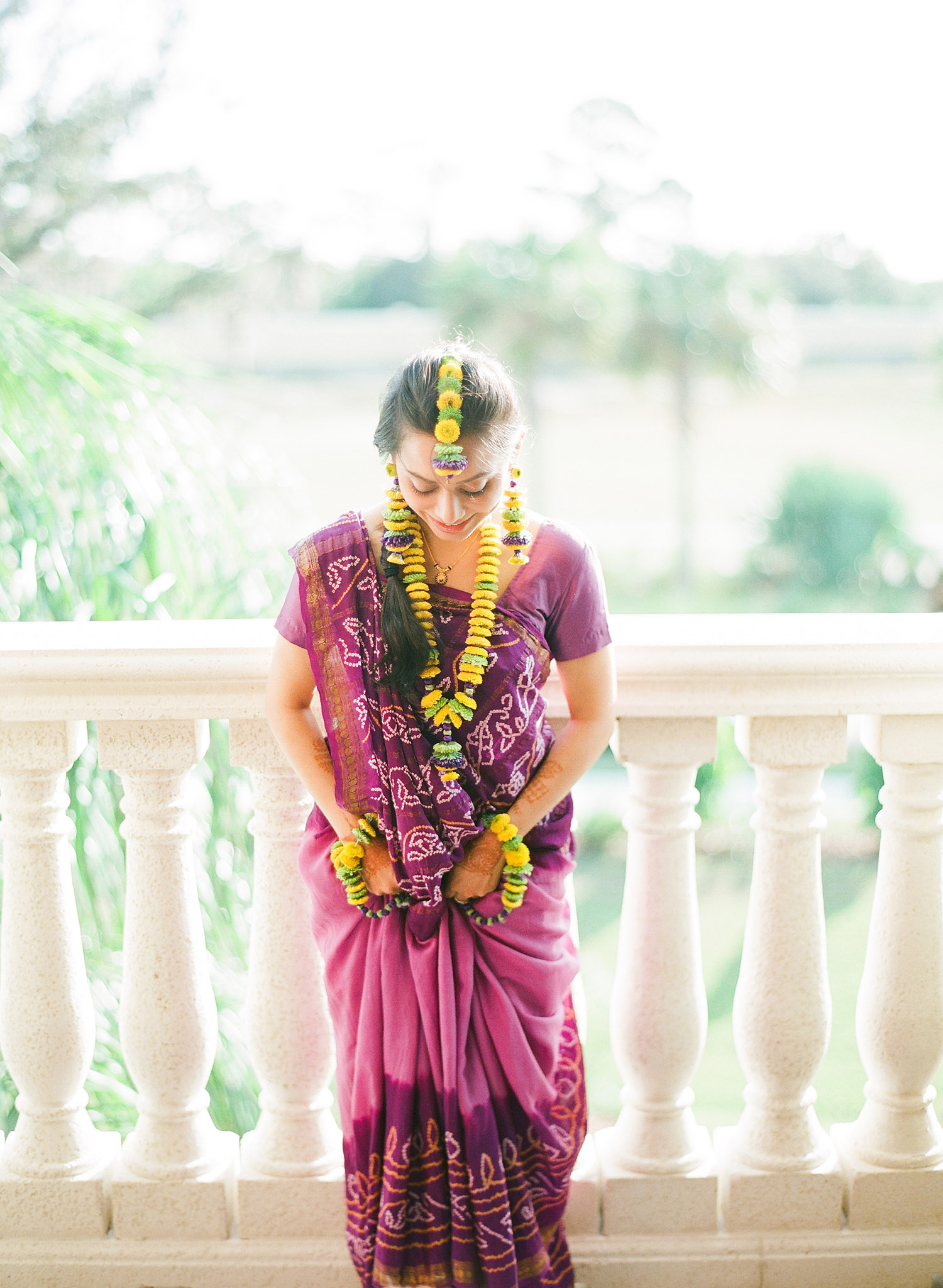 indian bride at her mehndi ceremony wearing a simple purple sari for her mehndi ceremony and yellow floral jewelry and floral tikka headpiece for her indian wedding in palm coast florida at the hammock beach resort photographed by Destination Wedding Photographer Lexia Frank, a top indian wedding photographer who shoots Indian weddings on film and shoots luxury indian weddings in florida and worldwide 