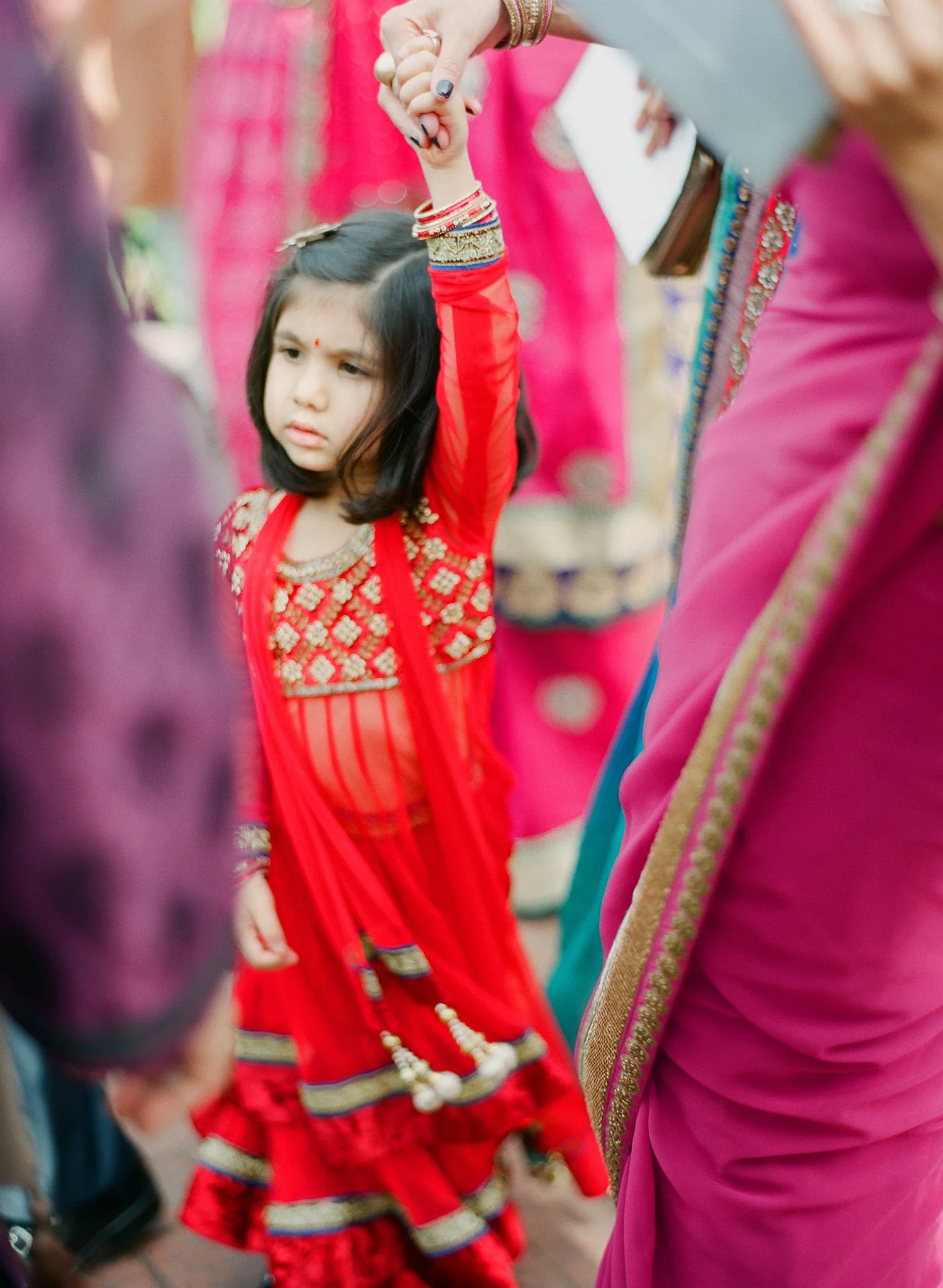 a little girl hold's her mother's hand during the parade at this Indian Wedding in Florida photographed by Destination Wedding Photographer, LExia Frank - a top indian wedding photographer - who shoots film for luxury indian weddings preferring the soft skin tones and vibrant colors for indian weddings in india and worldwide