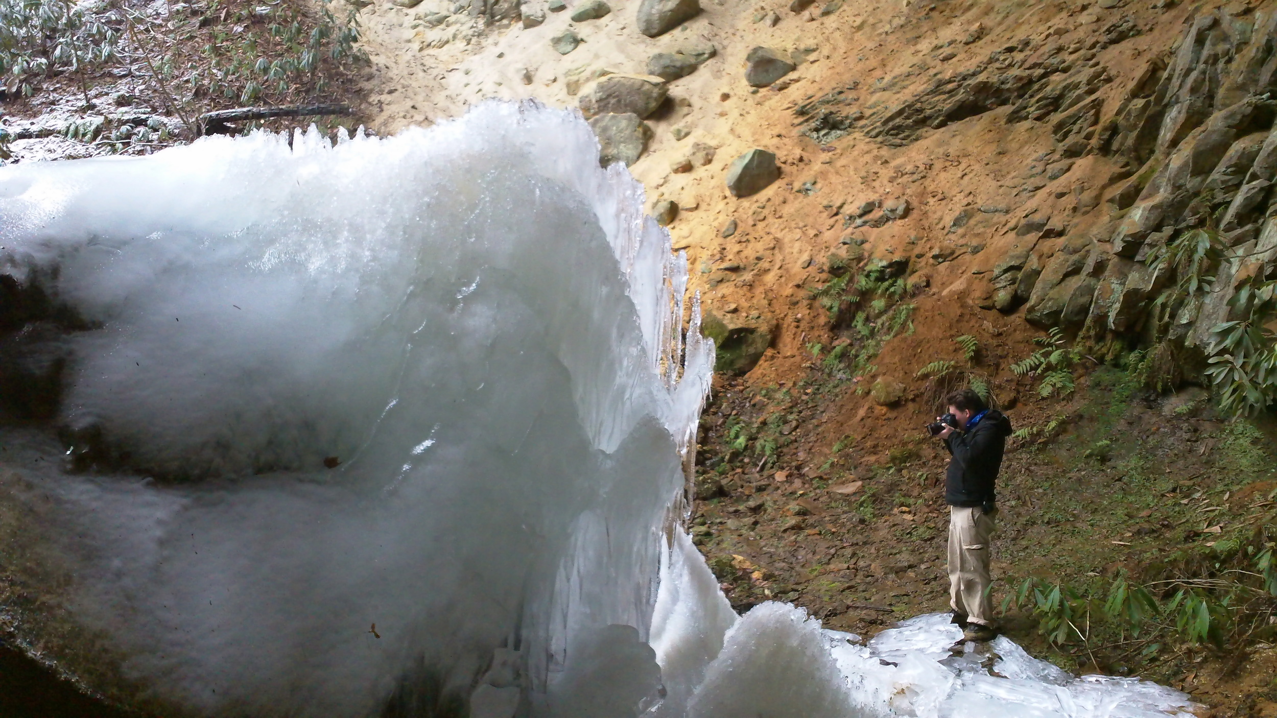 Nate Spicer photographing a ice formation formed by frozen water. Photo via Gerry James