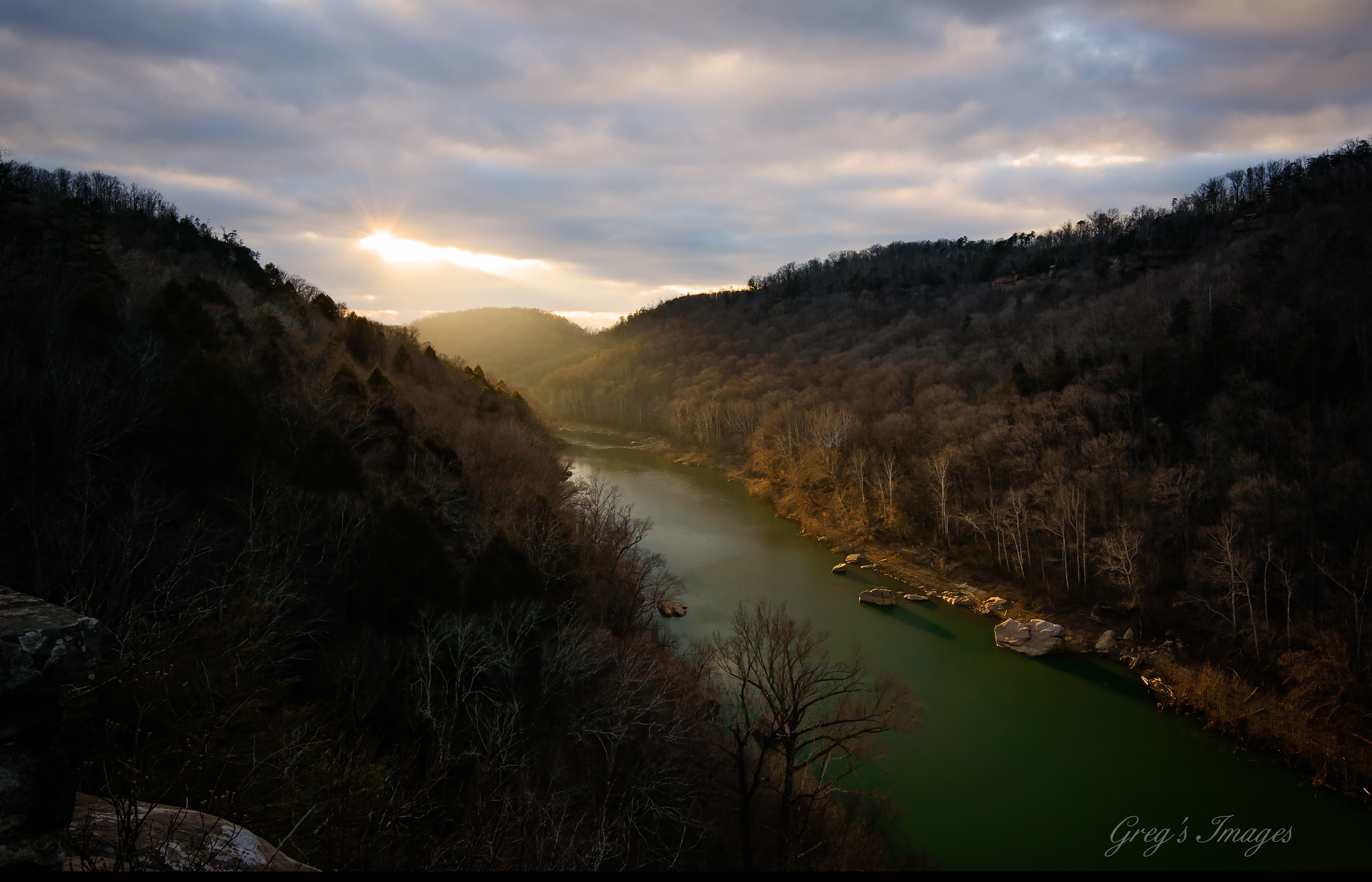 The evening sun breaking through the clouds and illuminating the South Fork River.