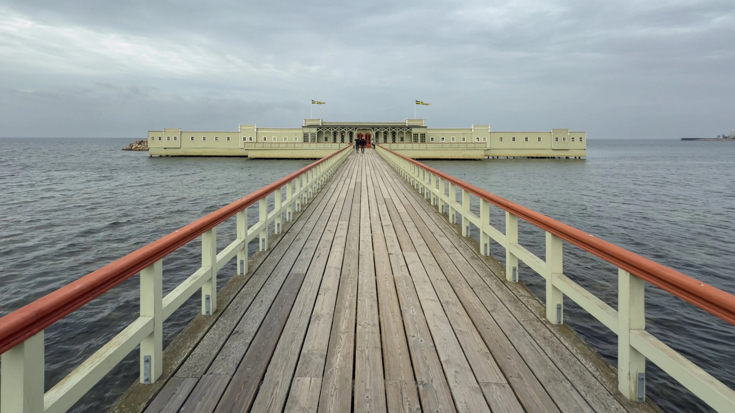 Wooden pier leading to Ribersborgs Kallbadhus bathhouse over the sea in Malmö under an overcast sky