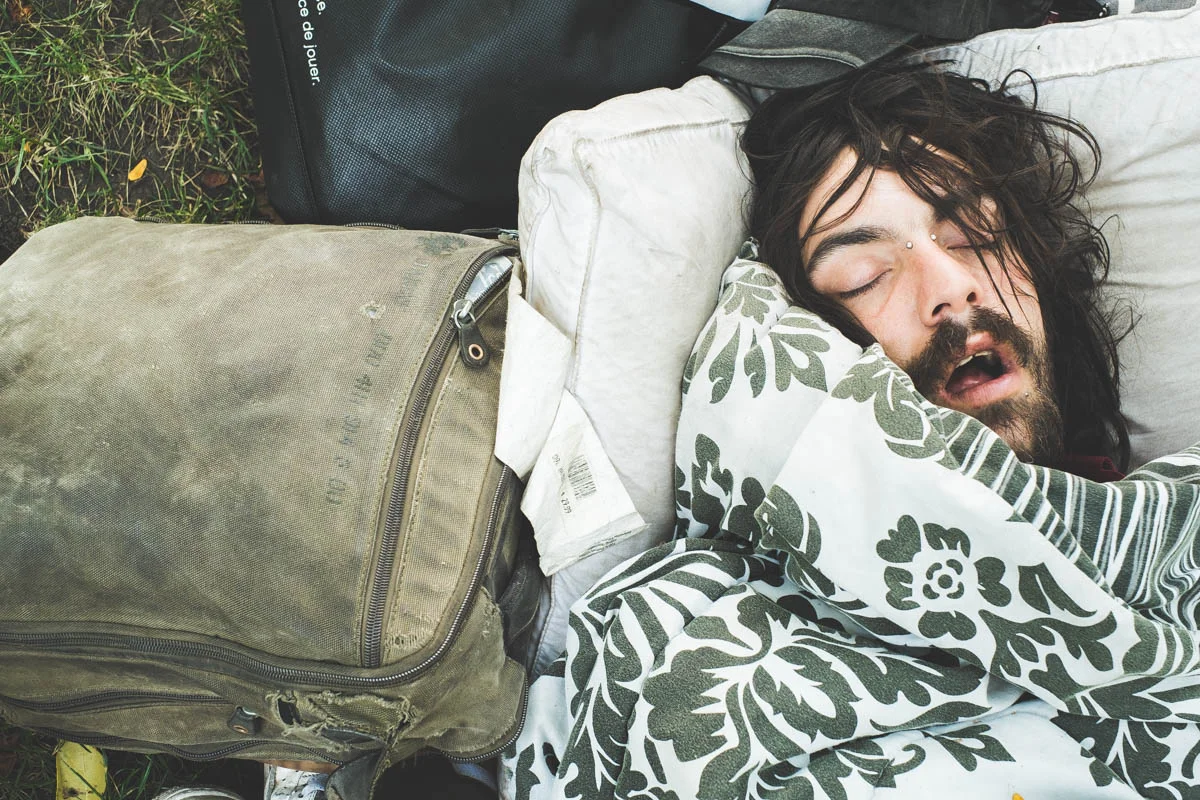 A man sleeps amongst his belongs in the church front yard. 