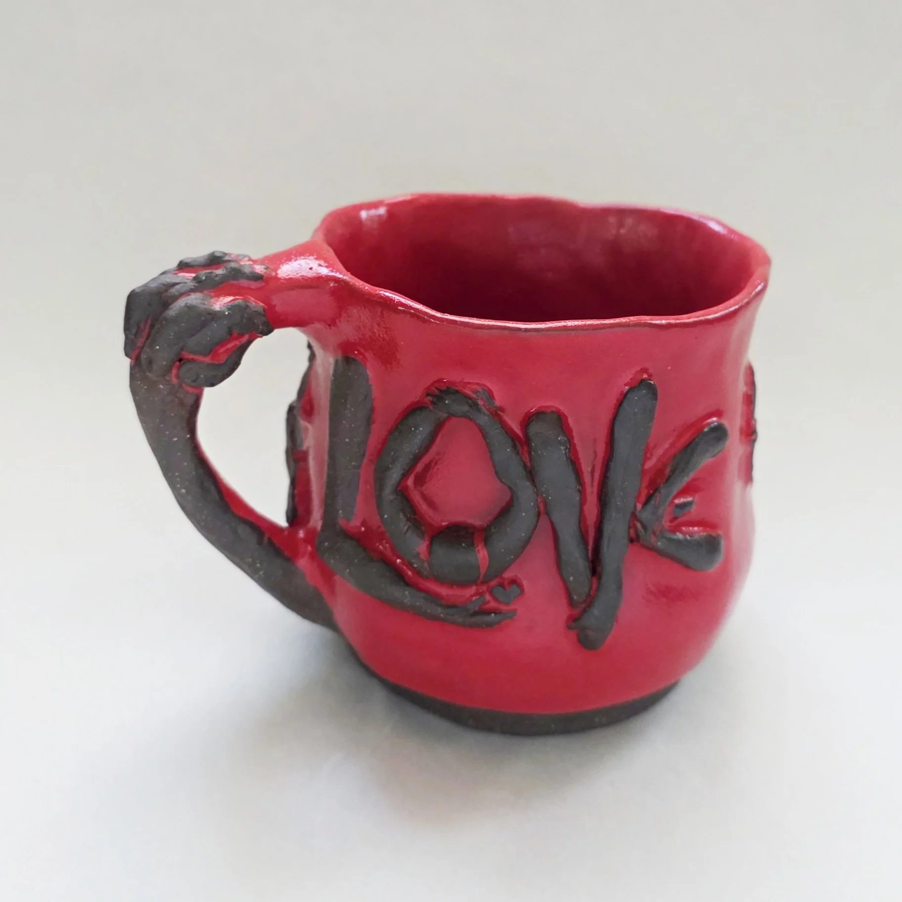 Dominique Larson,
Love thy Neighbor; Hand built mug with sculpted message, chocolate clay and red glaze, 4 3/4 x 3 1/4"
