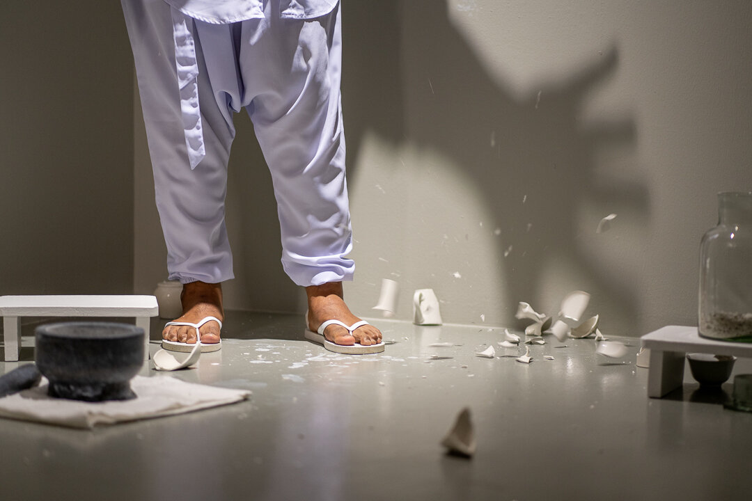 Ezzam Rahman  i should have kissed you when we were alone  (performance still) 2019 Painted wooden stools, granite urn, crushed porcelain from 38 white-glazed ceramic mugs, granite pestle and mortar, vintage medicinal glass jar, body paint Dimension