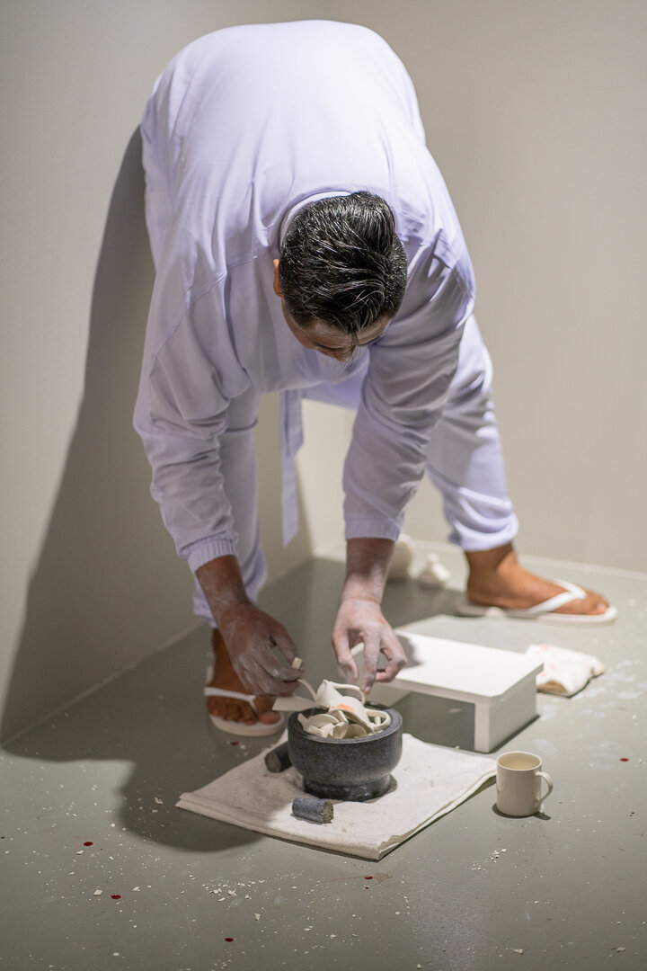  Ezzam Rahman  i should have kissed you when we were alone  (performance still) 2019 Painted wooden stools, granite urn, crushed porcelain from 38 white-glazed ceramic mugs, granite pestle and mortar, vintage medicinal glass jar, body paint Dimension