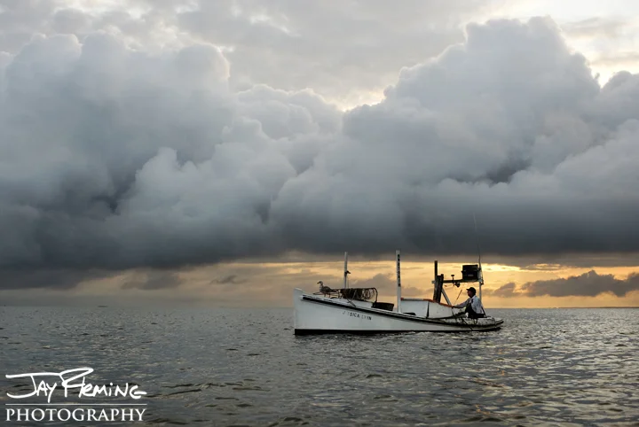 A early morning passes over Tangier Sound as a crab scraper pulls over a grass bed. Smith Island, Maryland 