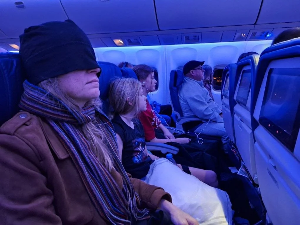 March wearing TRU47 emf protection hat on redeye flight to sleep