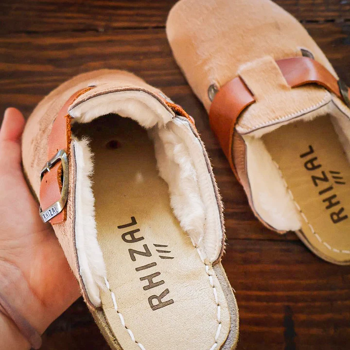 hand holding rhizal kuyu grounding shoe with copper over a wooden table with the other grounding shoe