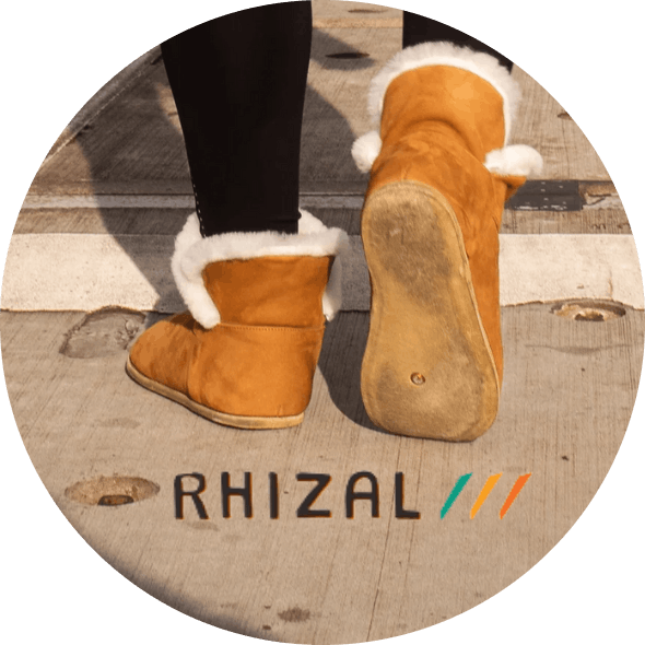 Rhizal ugg-style grounding boots with copper and leather soles on pavement with Rhizal logo