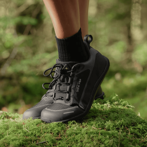 wearing bahe rewild waterproof grounding sneakers for trail walking and running on a mossy rock in the woods
