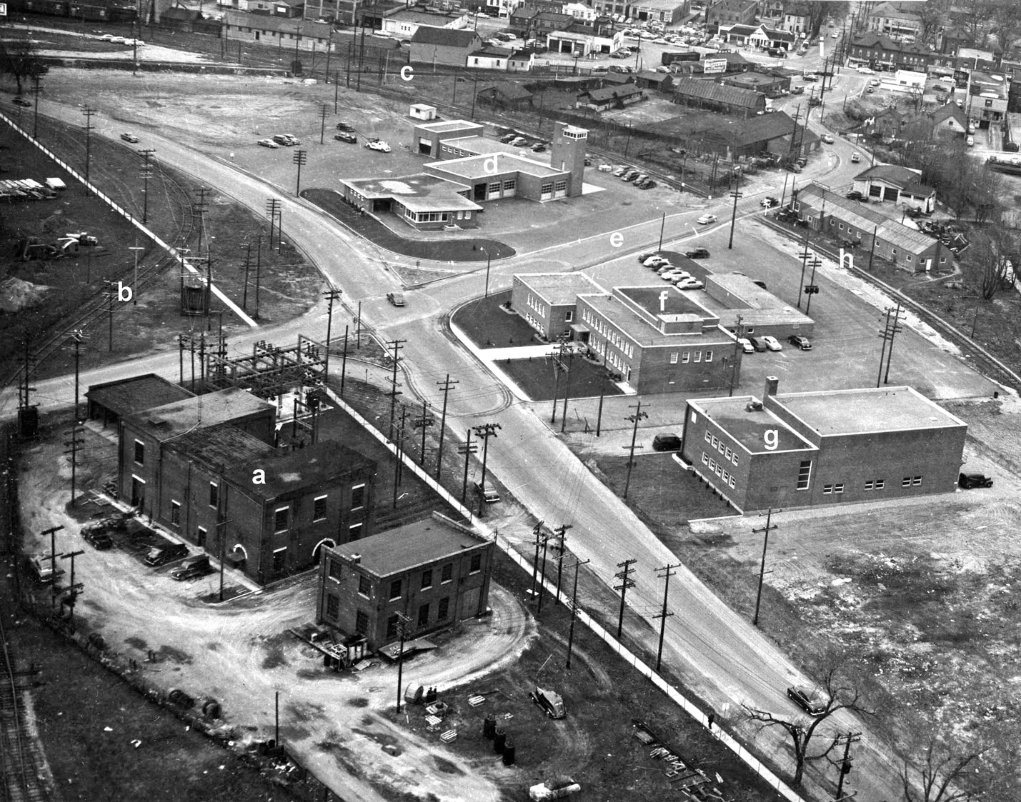 Aerial photo of Greenwich St, 1955. Image courtesy of the Brant Historical Society a) Brantford Hydro substation, b) CNR connecting track to the Toronto, Hamilton & Buffalo Railway (TH&B), c) CNR rail line to Tillsonburg, d) Fire Station, e) Newport Street, f) Police Station, g) Masonic Temple. Brantford Mosque since 2005, h) Former Brantford Hamilton Electric Radial Railway line, i) Clarence Street.