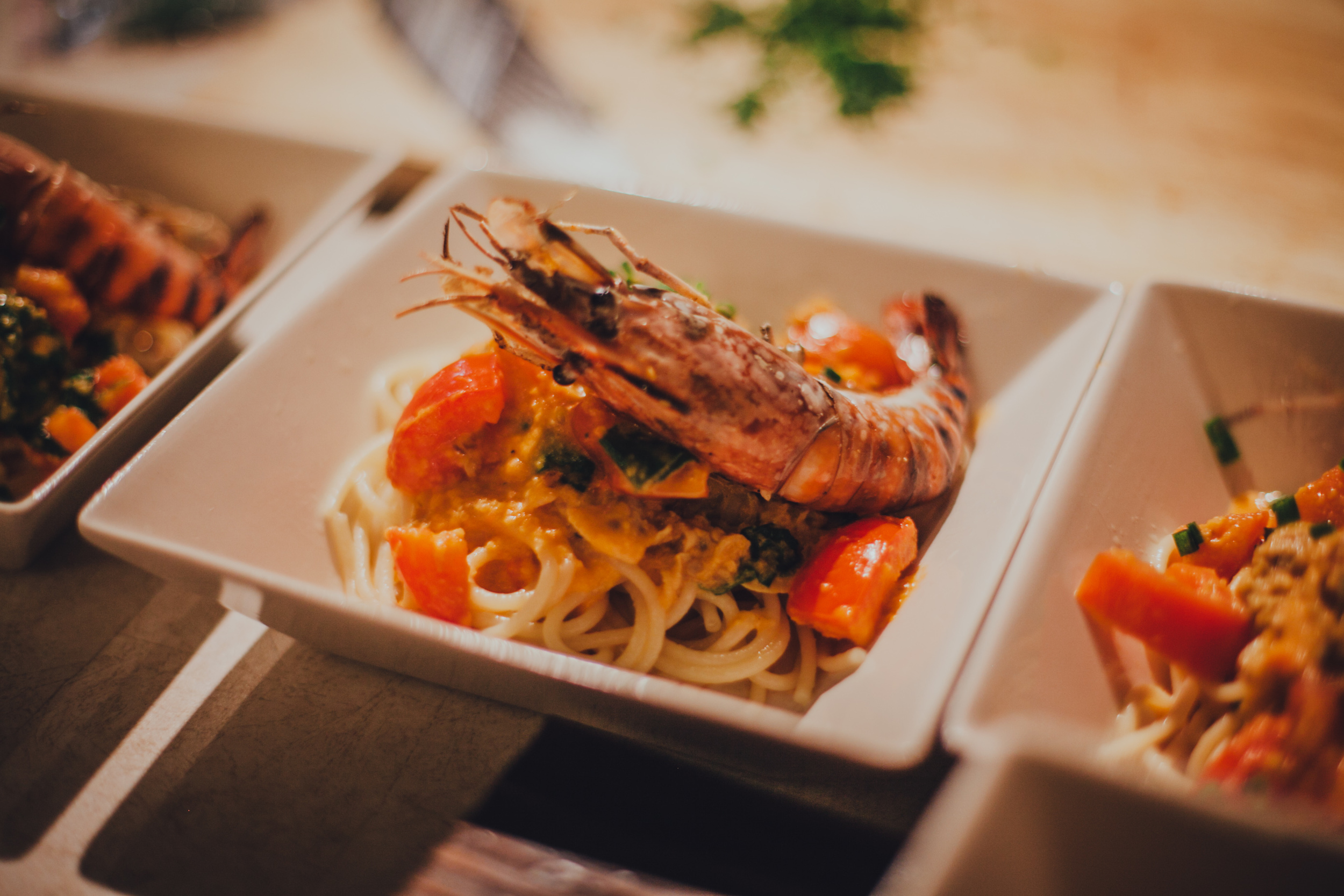 Pasta tossed in a seafood-based sauce, served with tomatoes, clams and grilled prawns.