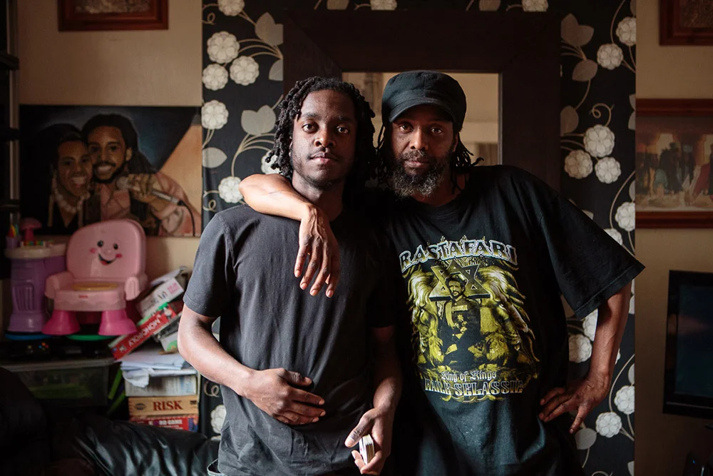 Joel and his Dad, Iyan in their front room, London Fields, 2015 At 20 years old, Joel is now an apprentice electrician with a view to getting into the property game of refurbishing houses and selling them for profit. Rastafarians, their family is peace loving and dedicated to their community. They live in a three story Victorian terrace in a spot that became the first and most gentrified area of Hackney despite ongoing gang violence. 