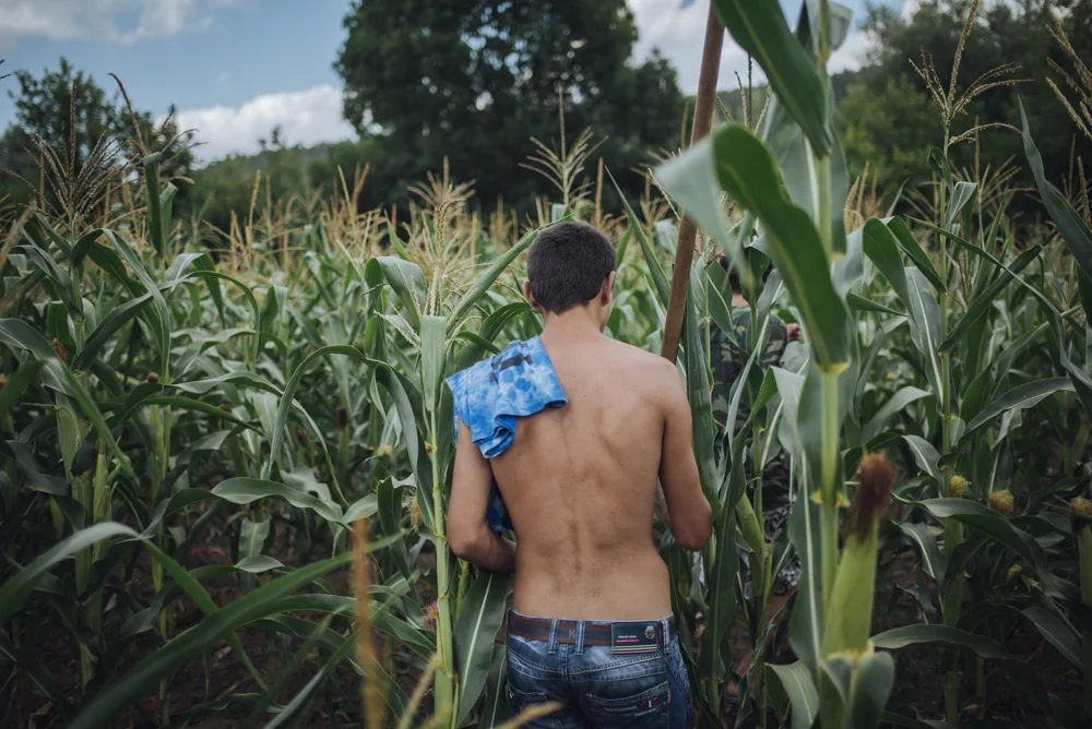 Most of the youth in the villages are doing agriculture. Dima is walking across the corn field to weed his vegetable patch. 