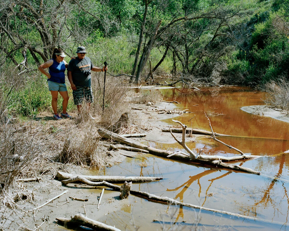 Million gallon saltwater spill site near Bear Den Bay, Ft. Berthold Reservation, July 2015 A year after this toxic wastewater flowed downhill through a ravine to Lake Sakakawea, Lisa & Walter DeVille examine the still-contaminated spill area. Although tribal officials believe their water supply was not affected, a study conducted by Duke University researchers proves otherwise.