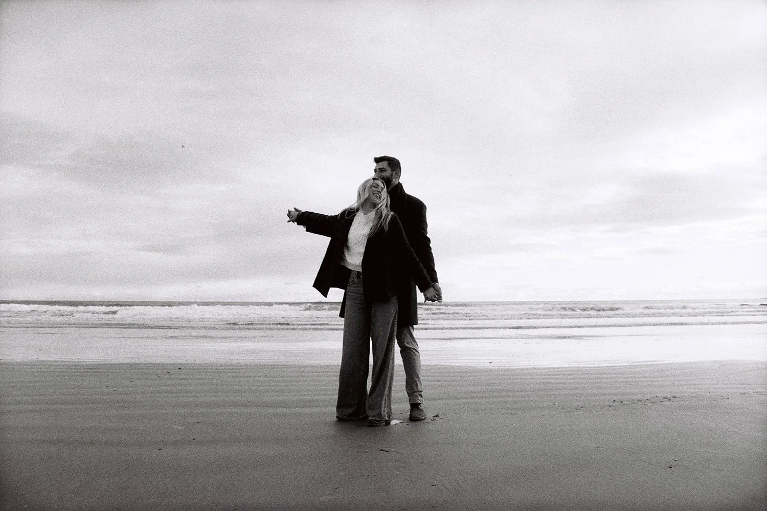 A couple having fun on the beach on black and white film