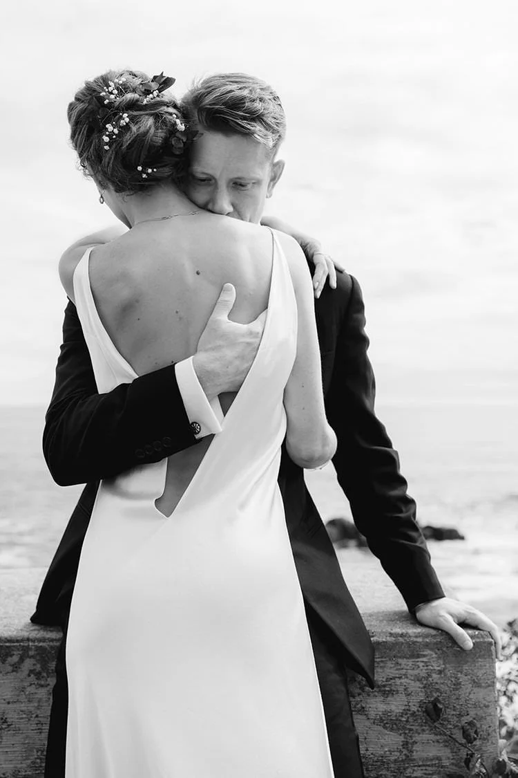 A groom embraces his bride with his hand on her back
