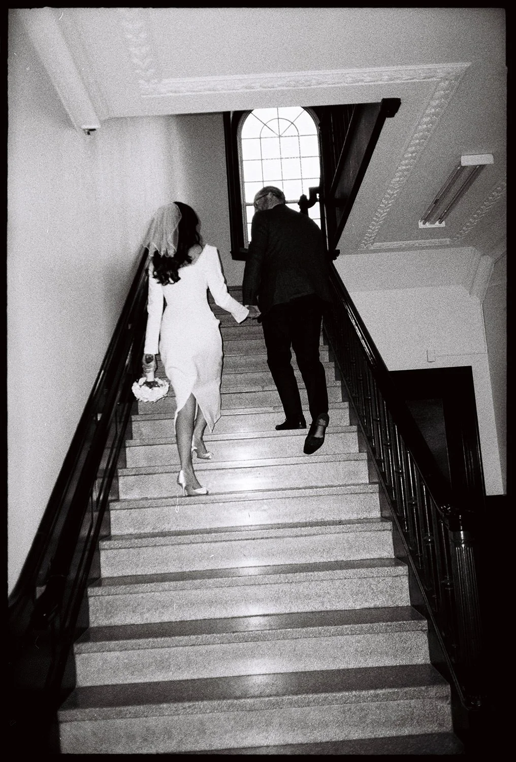 A courthouse elopement couple walks up steps in black and white film