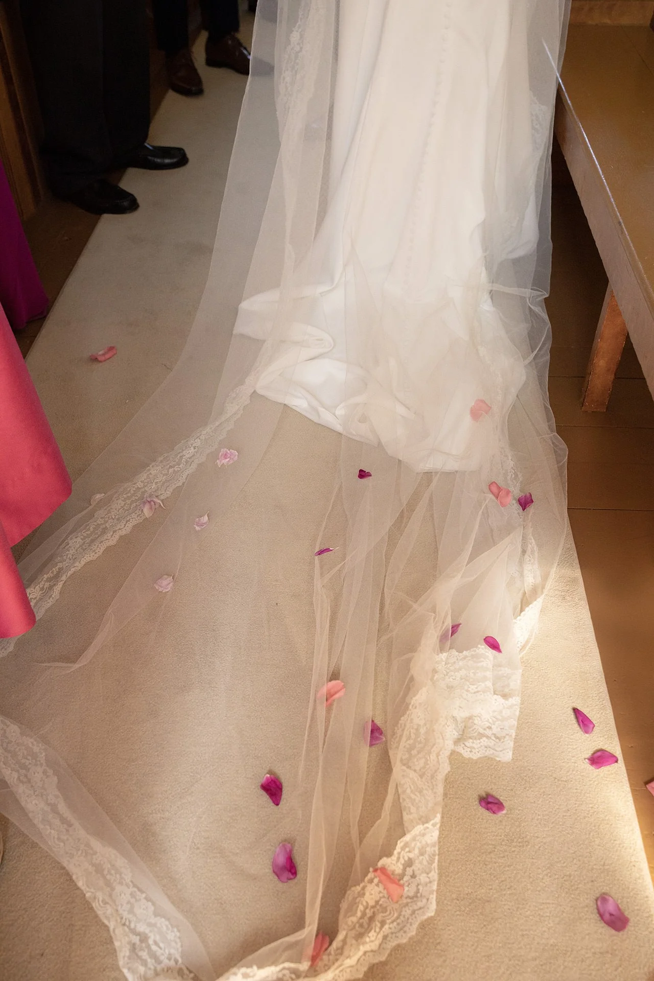 Red and pink flower petals on a bride's veil during their wedding ceremony