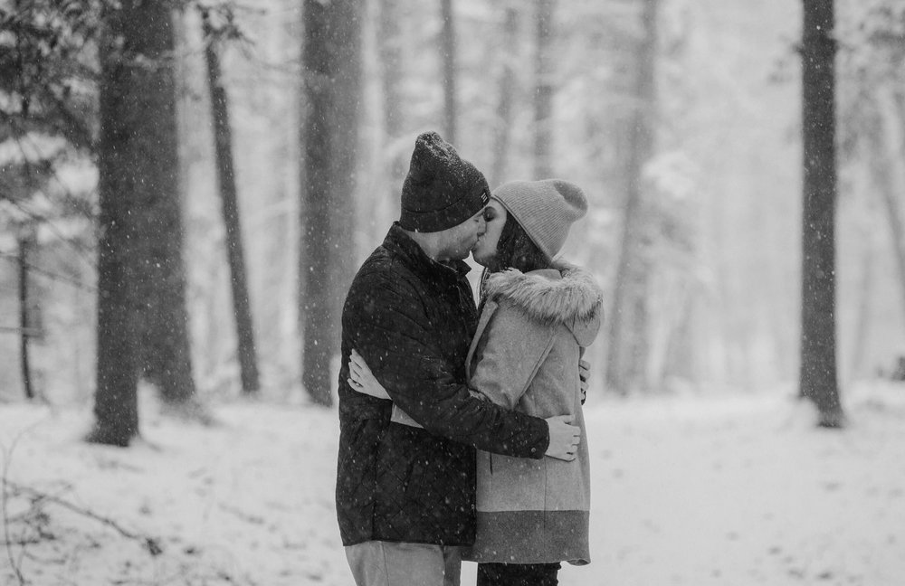  A couple kissing in the snow in the woods 