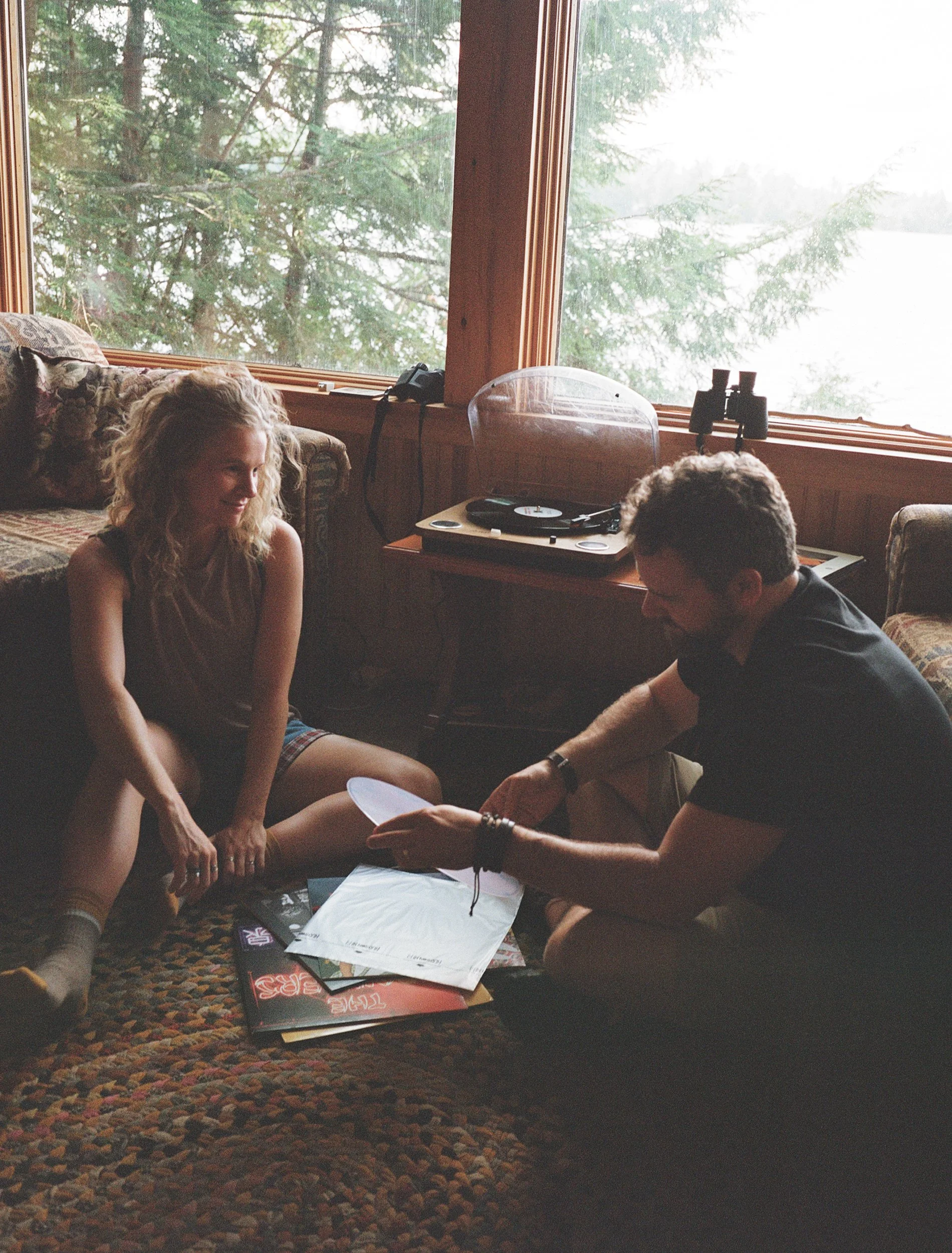 A couple looks at records on the floor in a Maine cabin. Shot on 35 mm color film