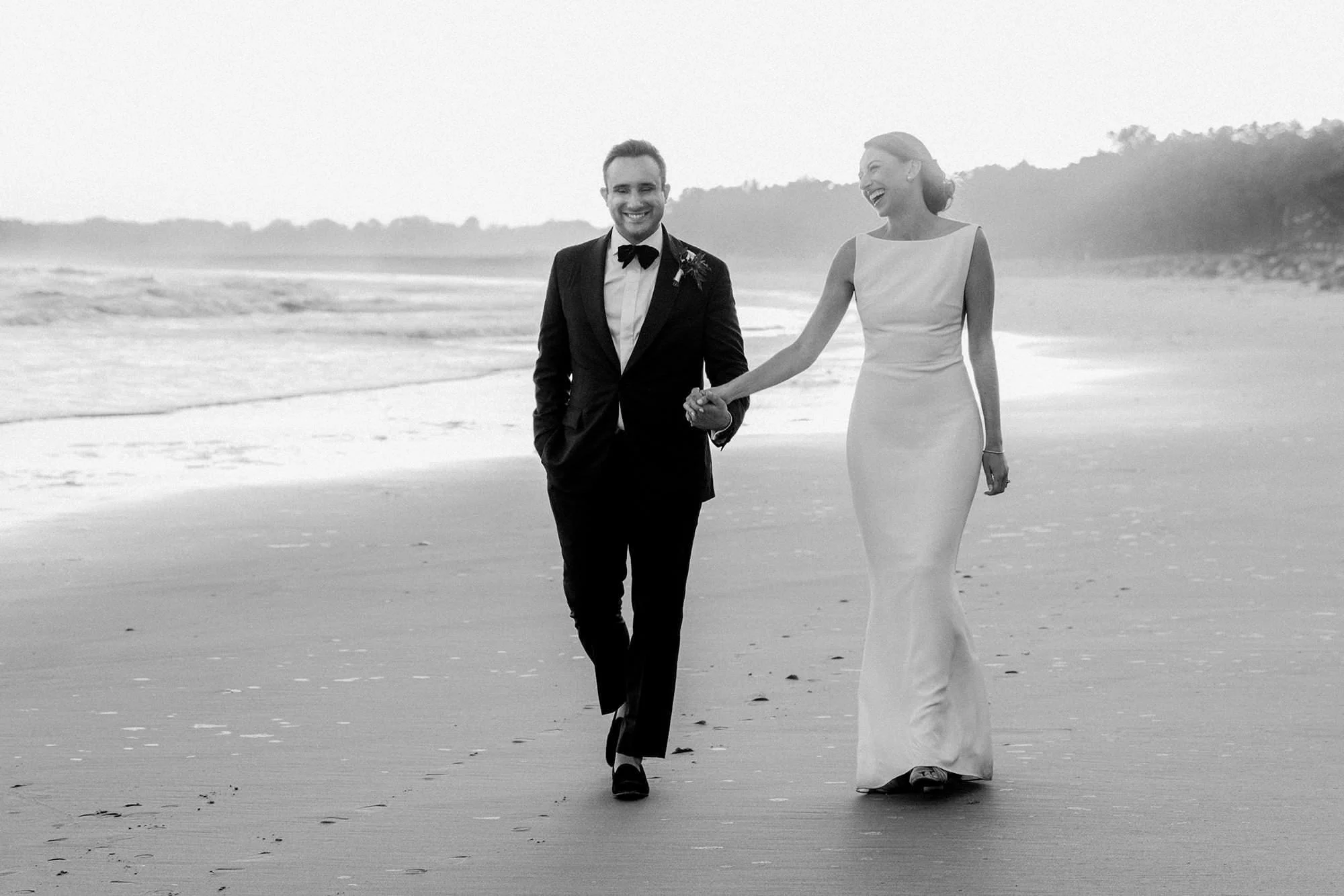A couple walks on the beach hand in hand