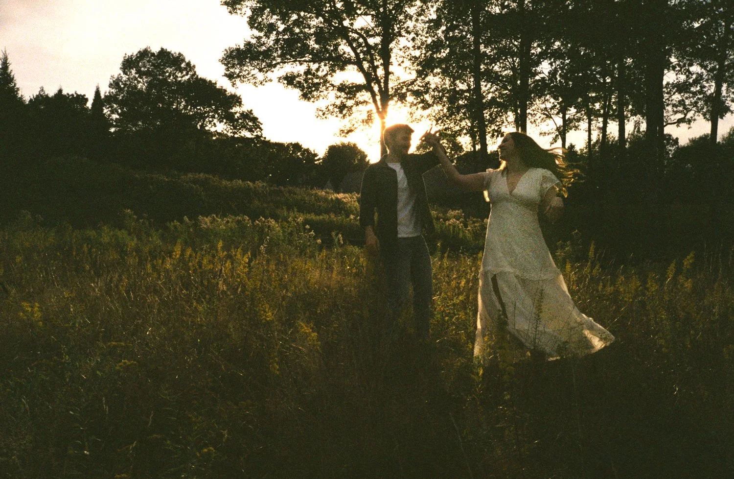 An engagement session at golden hour with the groom spinning the bride around on film