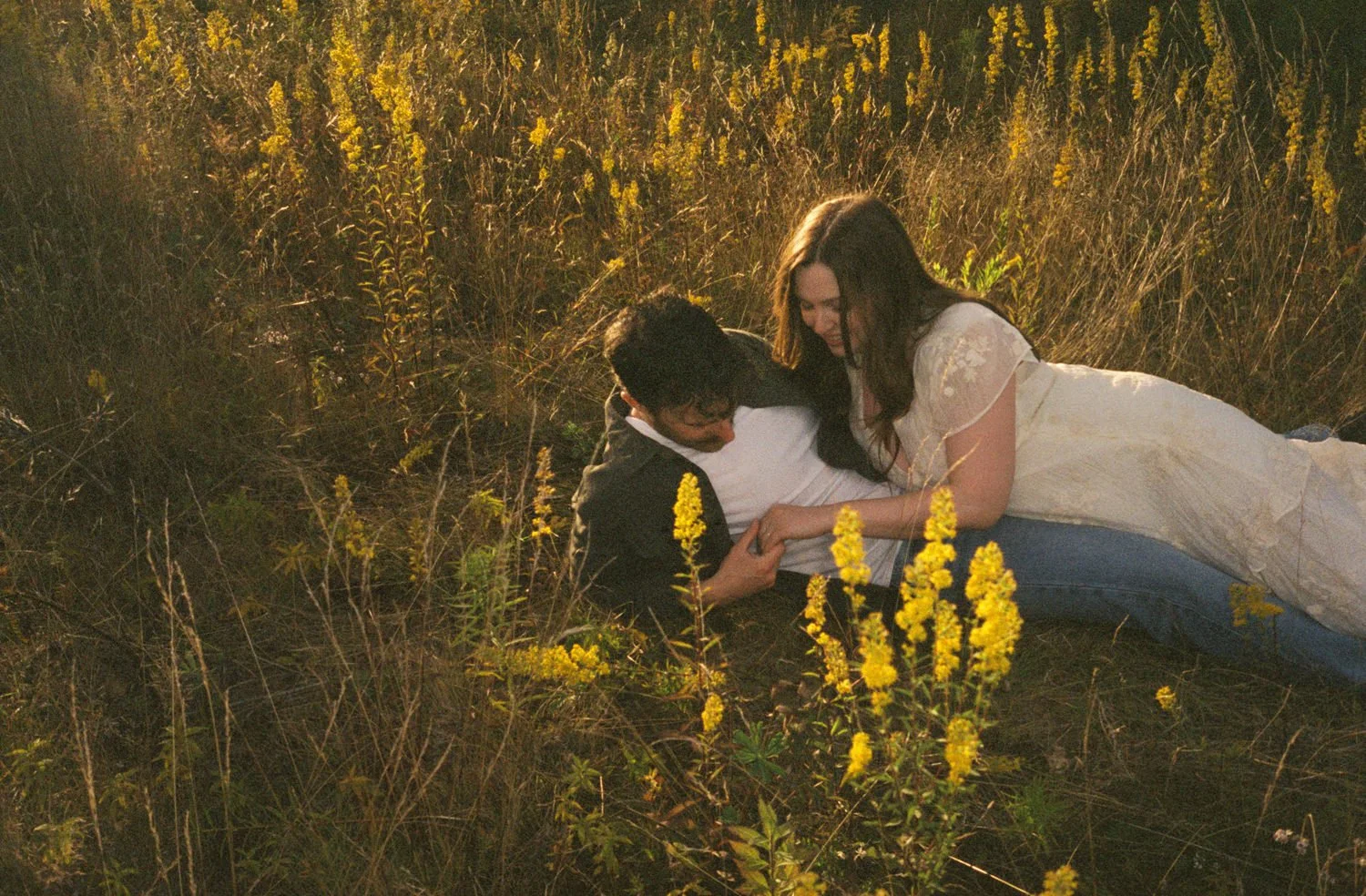 A couple lays in a field at golden hour