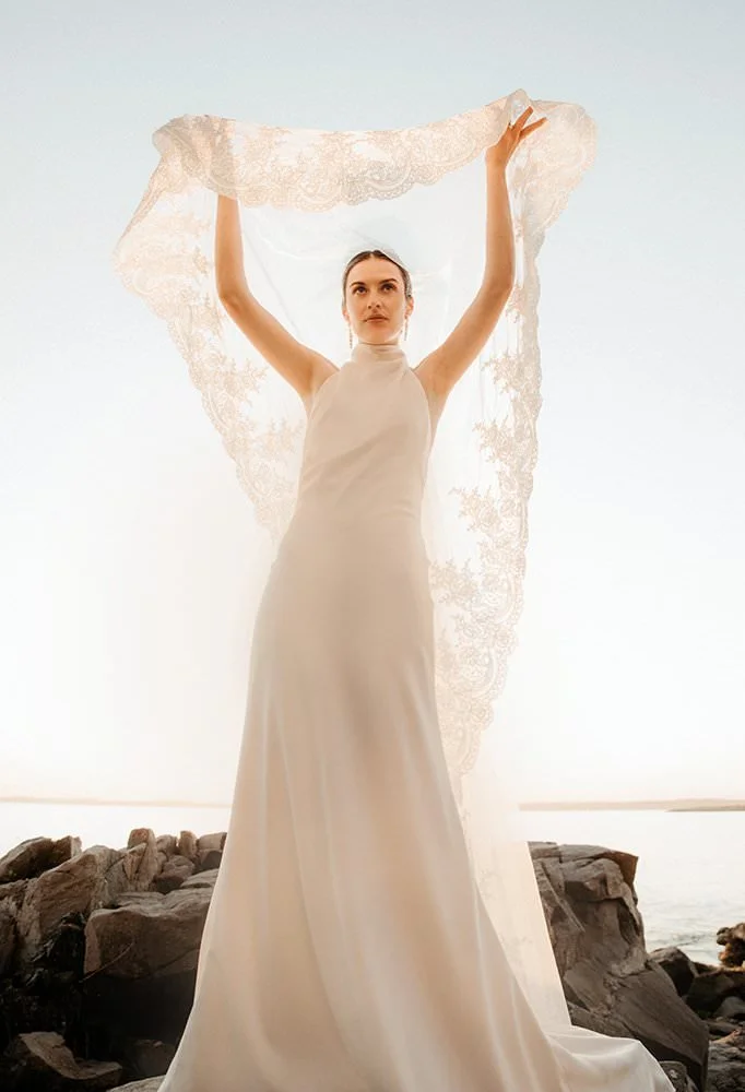 A stunning bride lifts her veil up over her head at golden hour