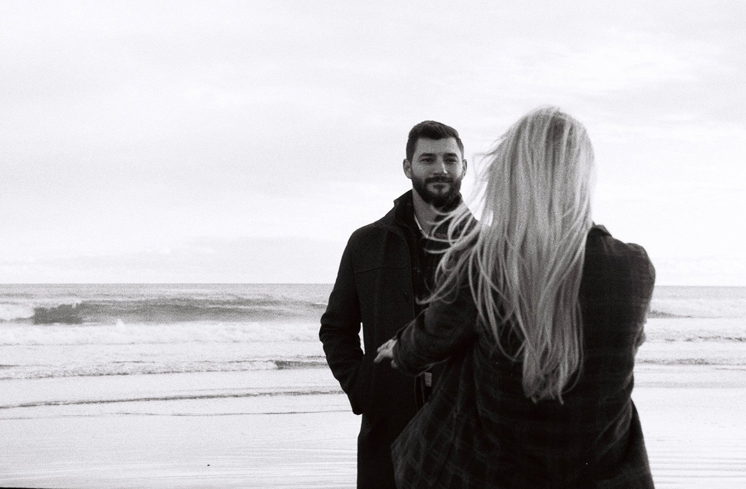 A woman reaching for a man on the beach in black and white film