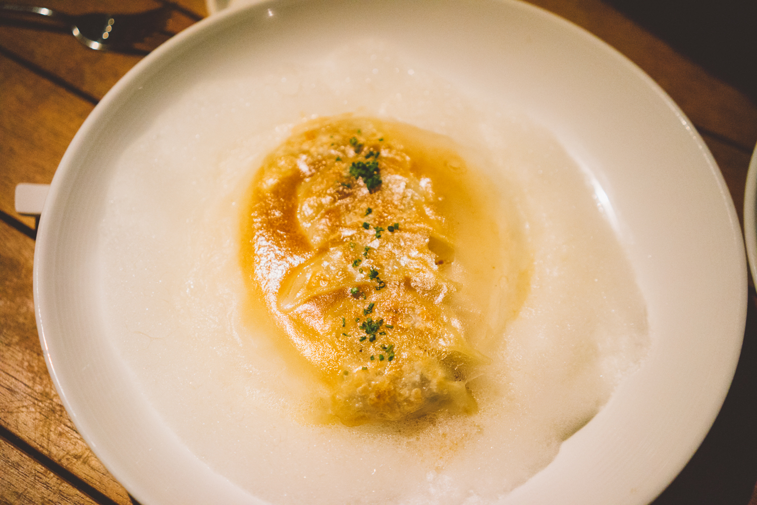 Six pork belly gyoza in a bacon foam, on top of a rustic tomato sauce.