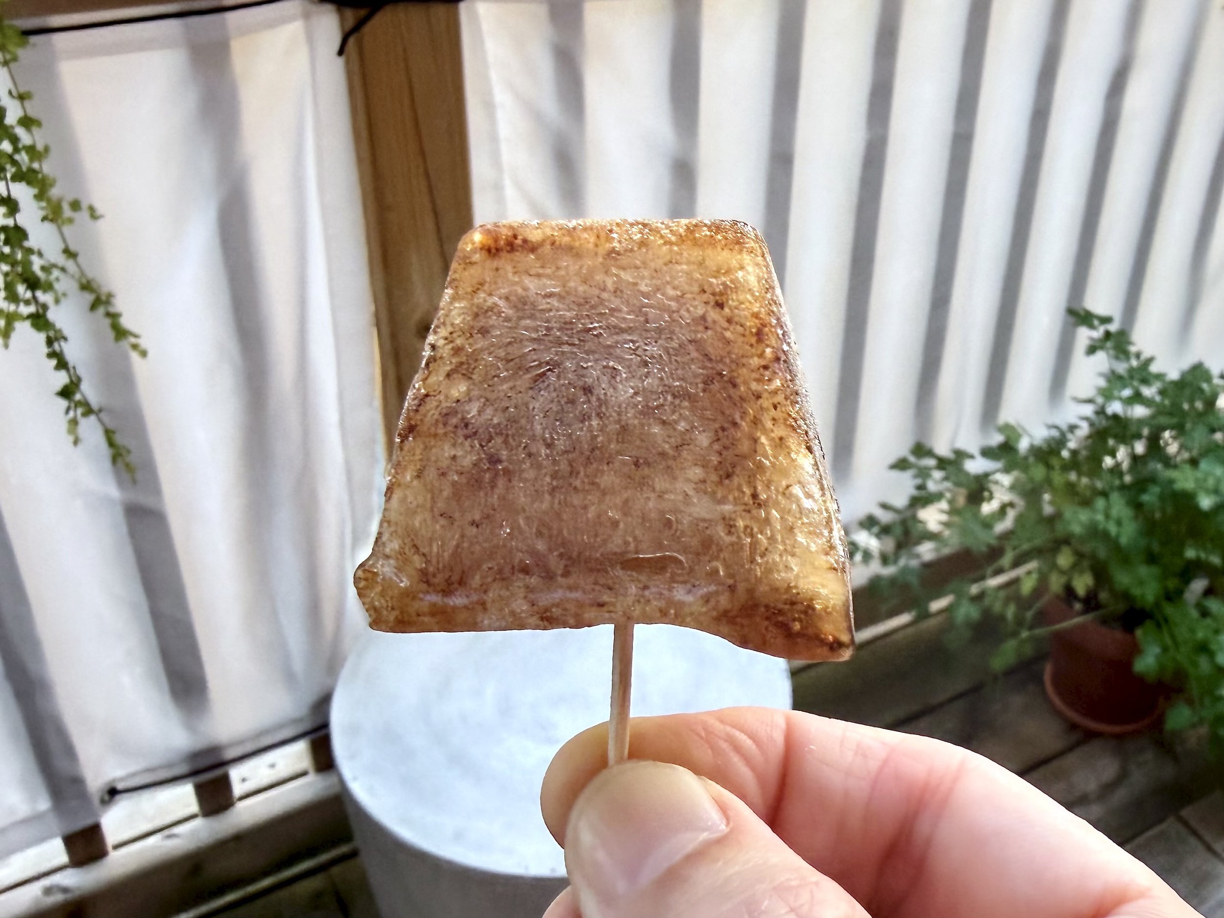 A frozen cola popsicle on a toothpick.