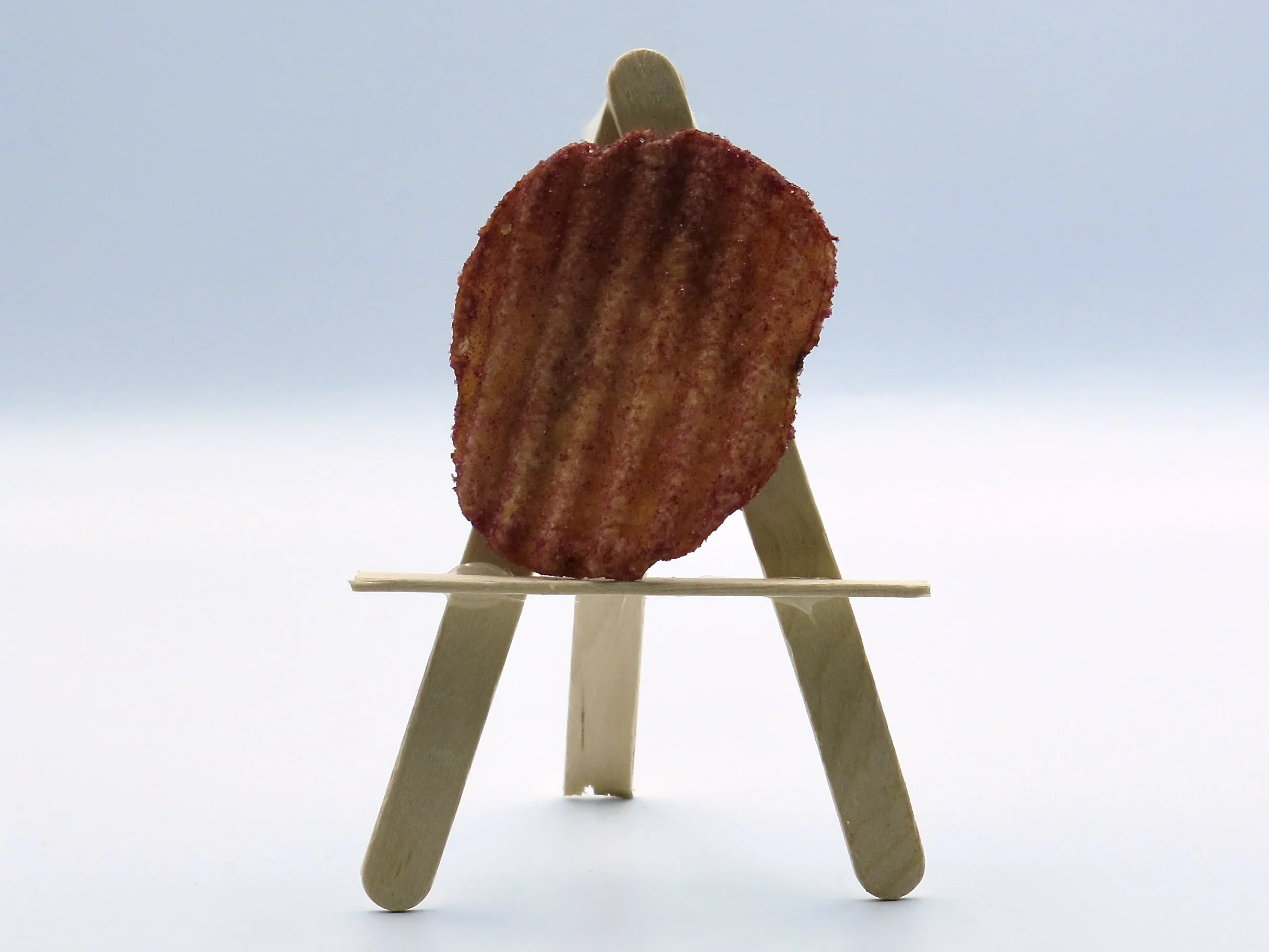 A PC Loads of Ketchup potato chip sitting on a popsicle stick easel